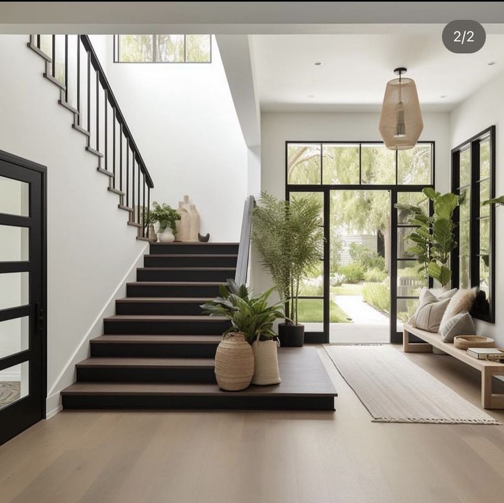 a staircase leading up to the second floor in a modern home with potted plants on either side