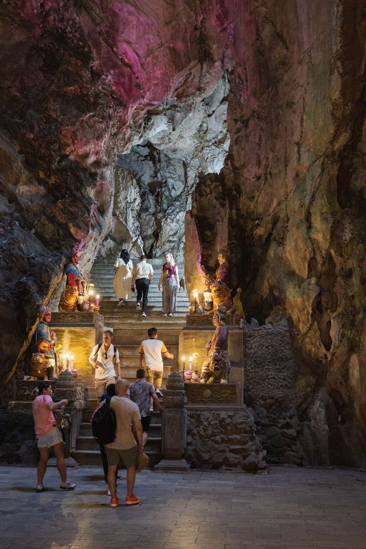 several people are standing in front of steps leading up to a cave with lights on them