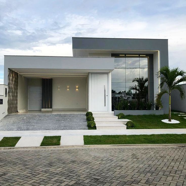 a modern house with grass and trees in the front yard