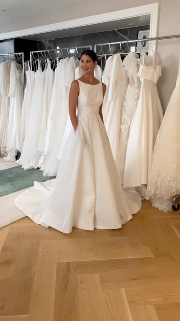 a woman is standing in front of some wedding dresses