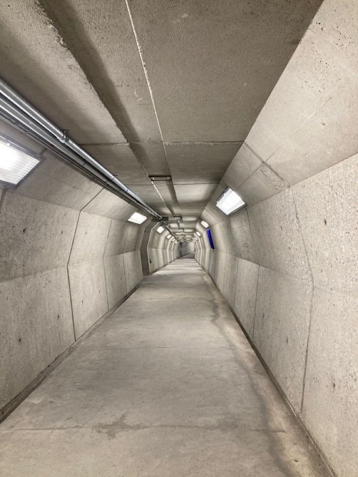 an empty tunnel with concrete walls and pipes