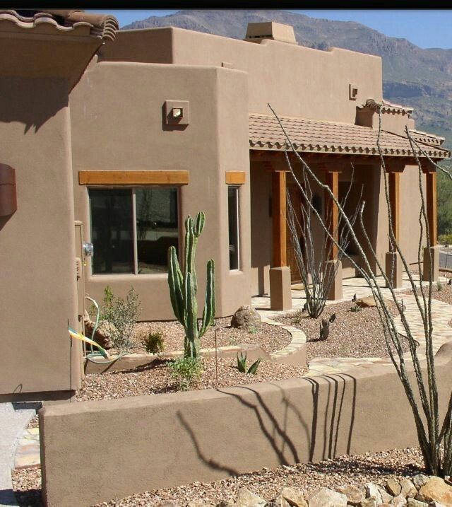 an adobe style house with cactus in the foreground and mountains in the back ground