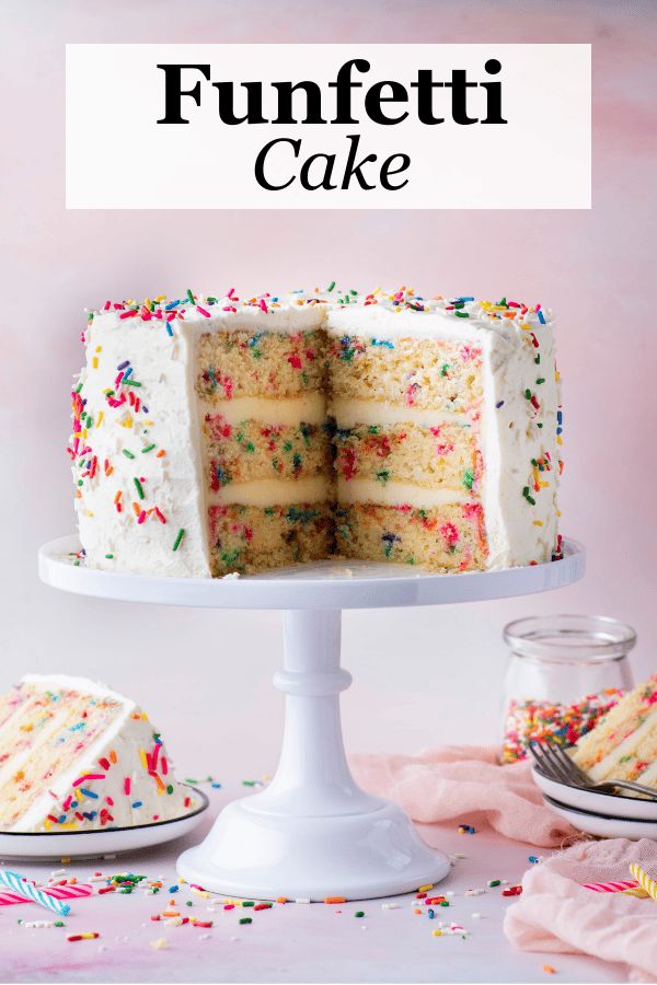 a cake with white frosting and sprinkles cut into slices on a plate