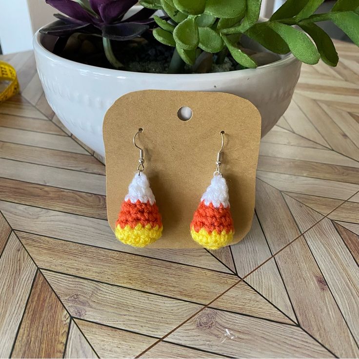 a pair of colorful earrings sitting on top of a table next to a potted plant