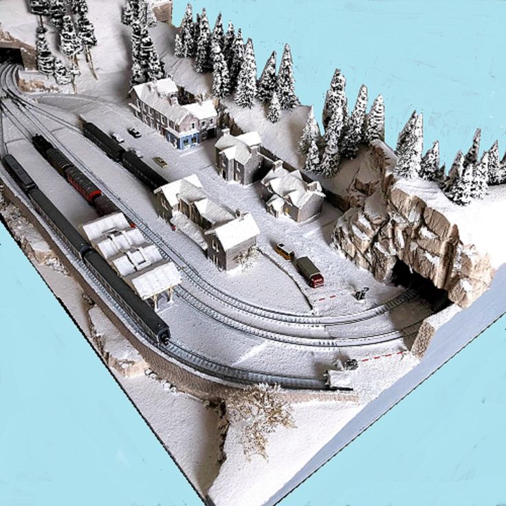 a model train set is shown with trees and snow on the ground in front of it