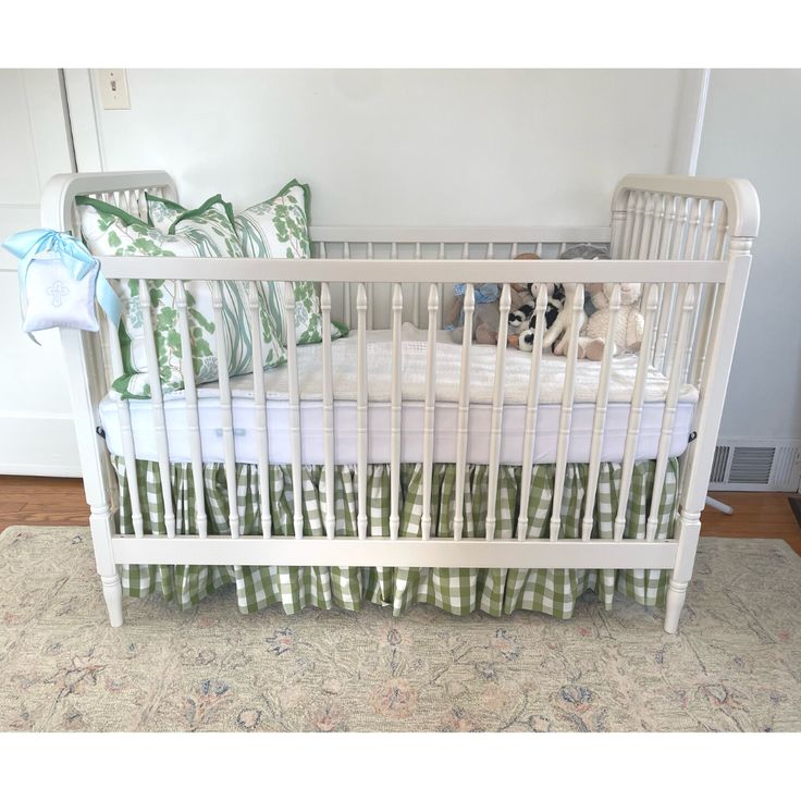 a white crib with green and white bedding