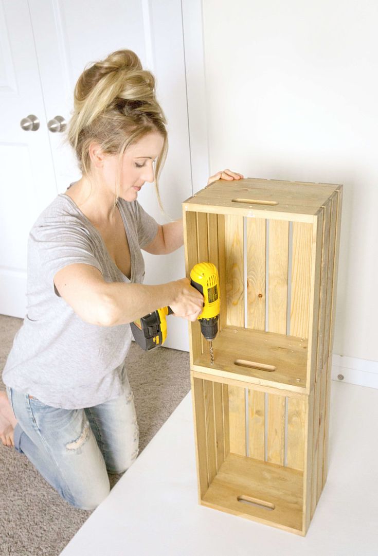 a woman using a driller on a wooden cabinet