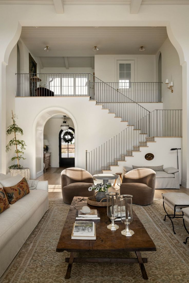 a living room with two couches and a coffee table in front of a staircase