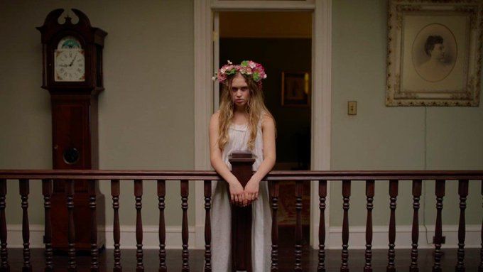 a woman with flowers in her hair is standing on a balcony looking at the camera