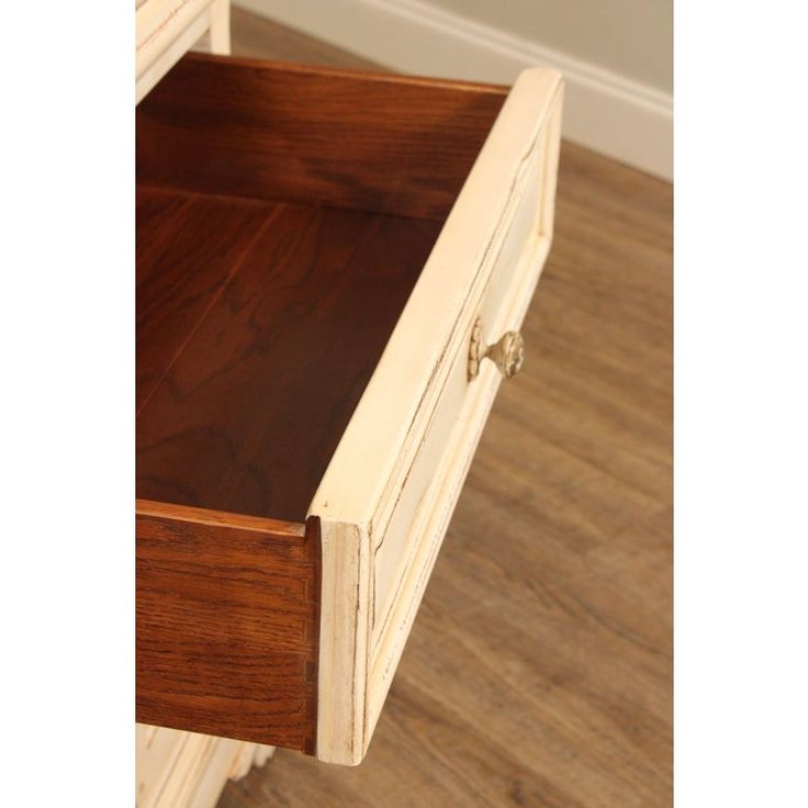 an open drawer on the side of a white dresser with wood grained flooring