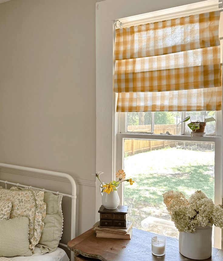 a bed room with a neatly made bed and a window covered in yellow checkered curtains