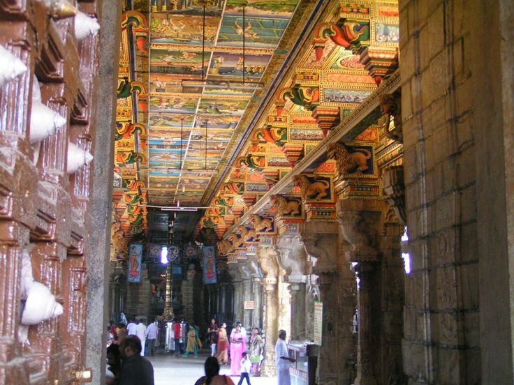 people are walking through an ornate building with colorful decorations on the ceiling and walls,