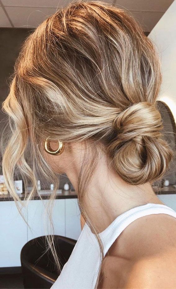 a woman with blonde hair styled into a low bun in a beauty salon, looking to the side