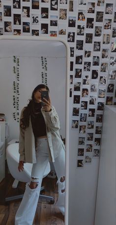 a woman taking a selfie in front of a mirror with photos on the wall