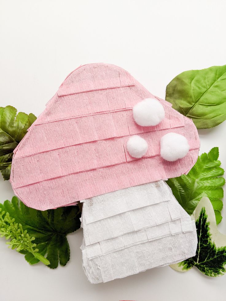 a pink mushroom shaped house sitting on top of green leaves