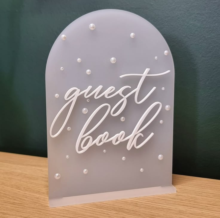 a light up sign that says guest book on top of a wooden table next to a green wall