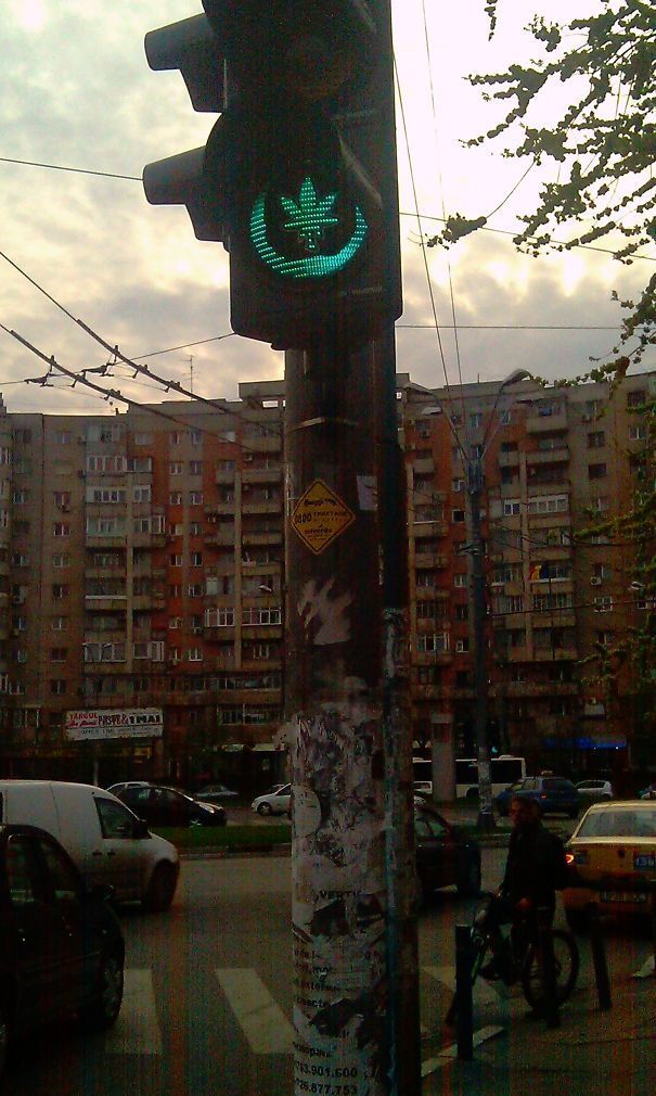 a green traffic light sitting on the side of a road next to a tall building