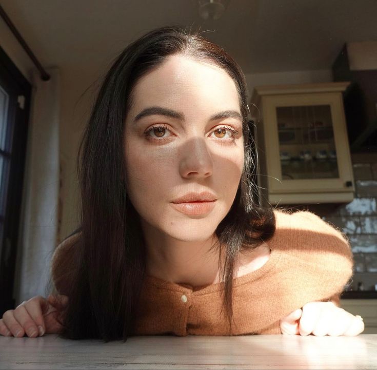 a woman laying on the floor in front of a window with her head tilted to the side