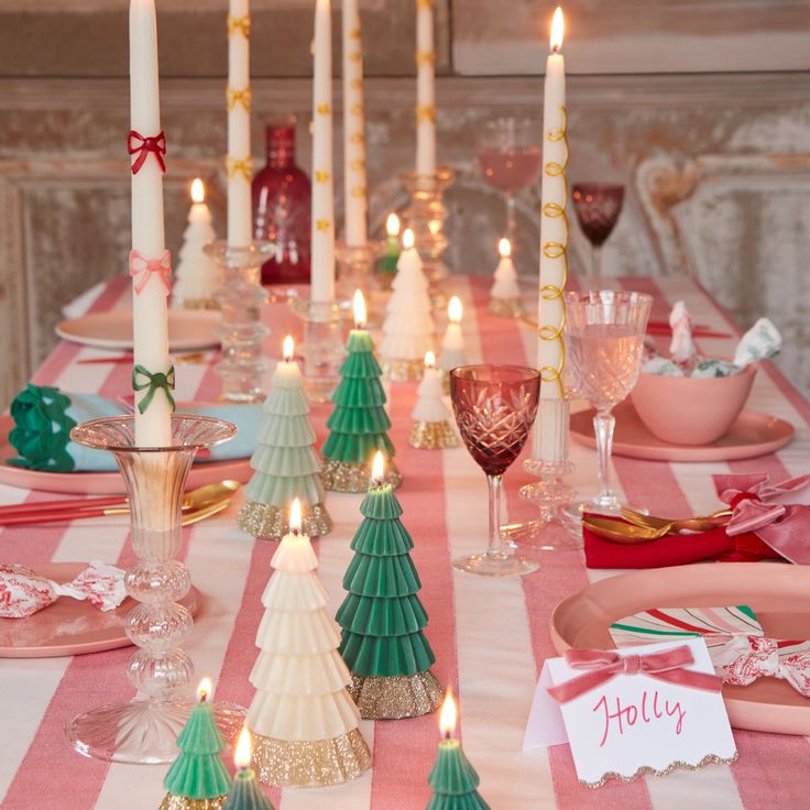 a table set for christmas with candles and place settings