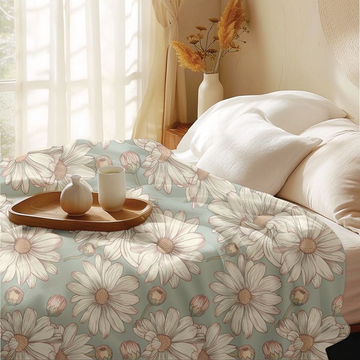 a tray with two cups on top of it next to a flowery bed spread