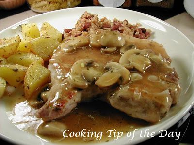 a white plate topped with meat covered in gravy next to potatoes and mushrooms