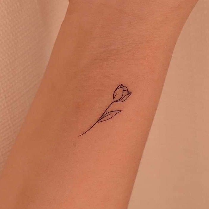 a single flower tattoo on the wrist is shown in black ink and has a thin line drawing