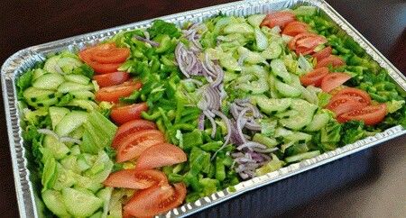 a tray filled with lettuce and tomatoes on top of a table