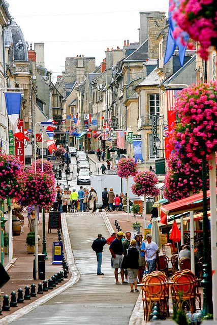 people are walking down the street in an old european town with many shops and restaurants