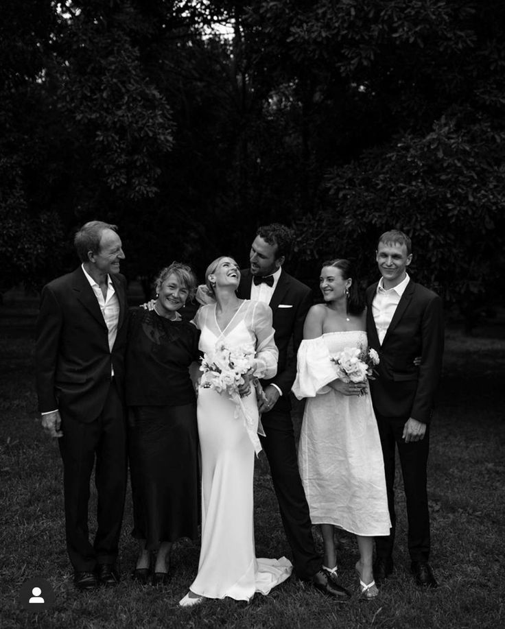 a group of people standing next to each other on a field with trees in the background