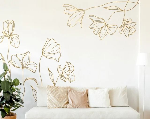 a white couch sitting in front of a wall with flowers on it