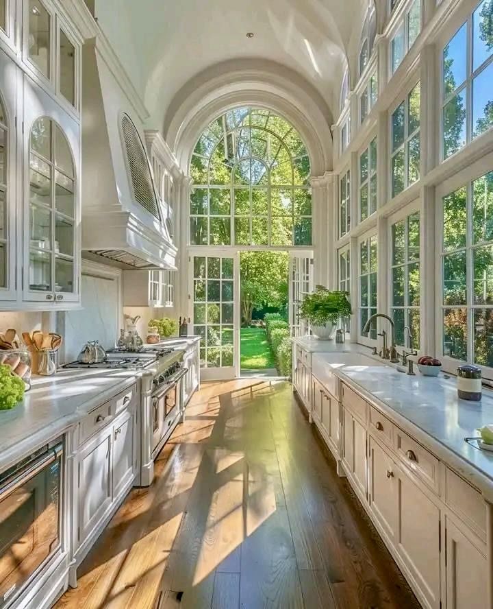 a large kitchen with lots of windows and white cabinets on both sides of the room