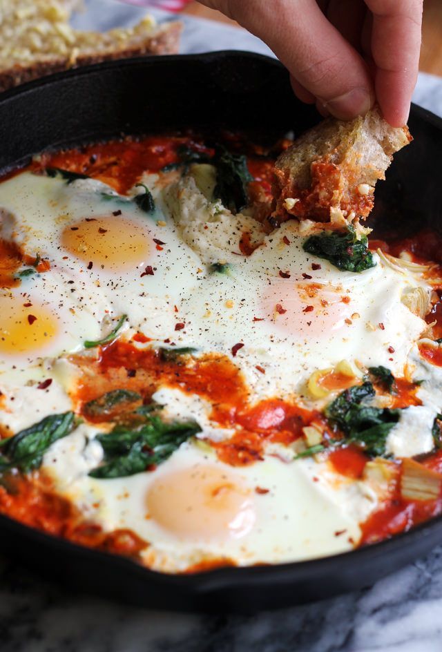 an egg is being cooked in a skillet with spinach and other toppings