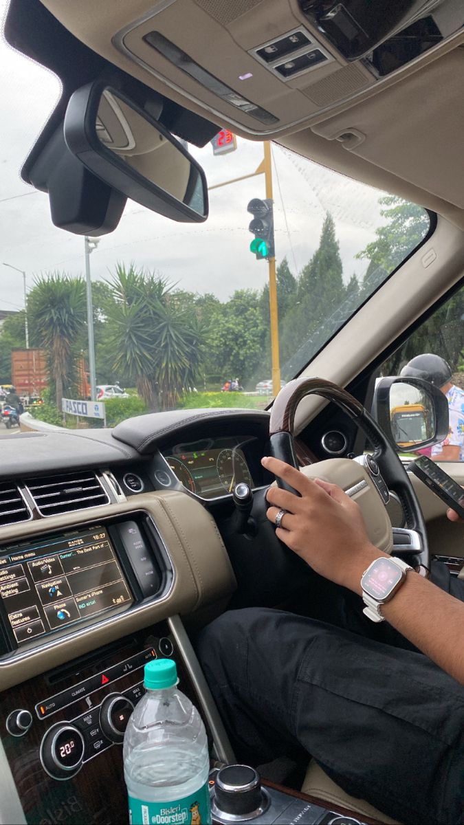 a man sitting in the driver's seat of a car with his hand on the steering wheel