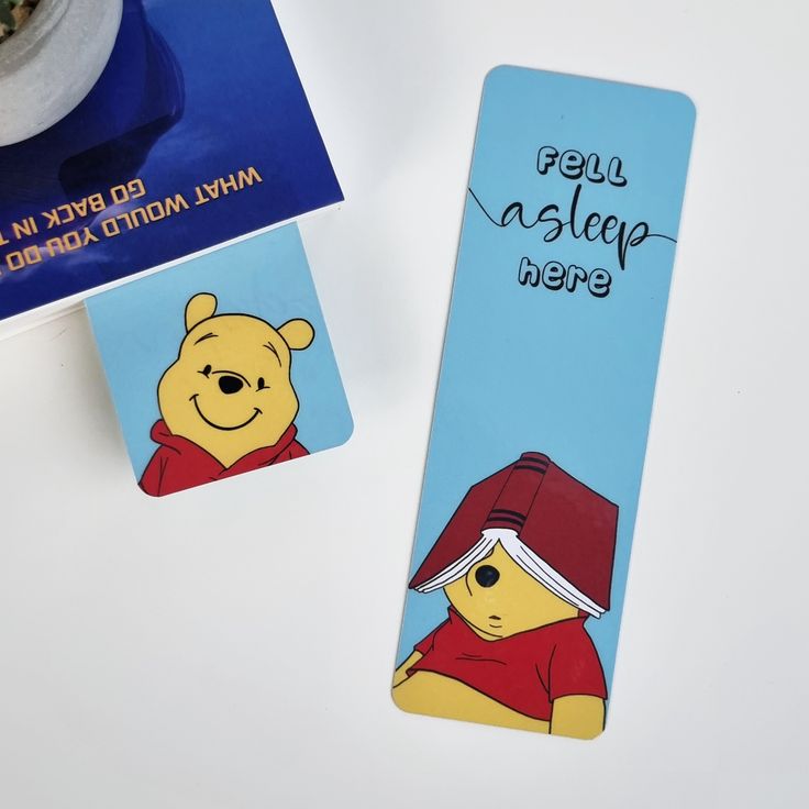 a winnie the pooh bookmark next to a cup of coffee on a table