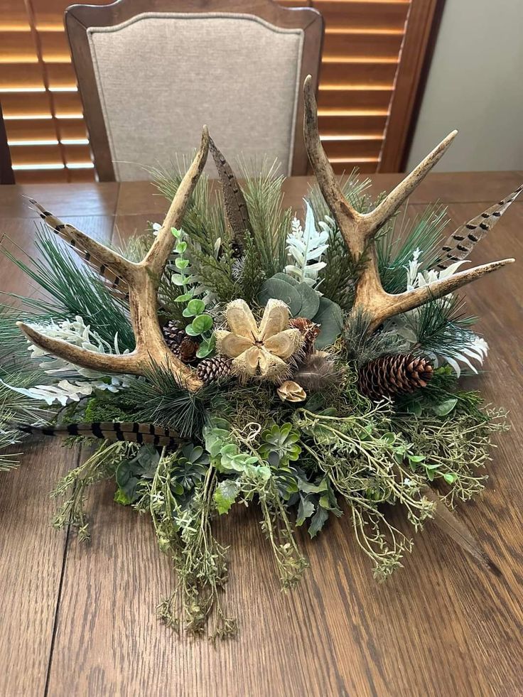 the centerpiece is decorated with deer antlers, pine cones and evergreen greenery