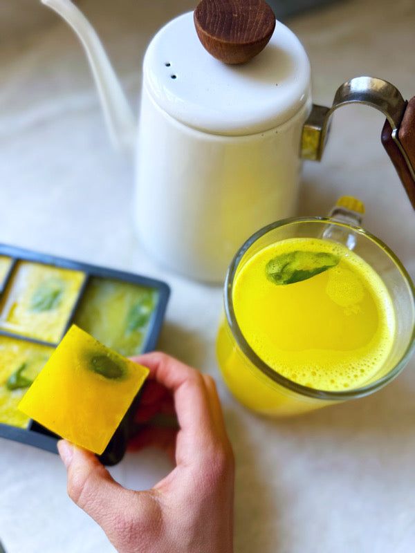 a person is holding some food in front of a teapot and cup on a table