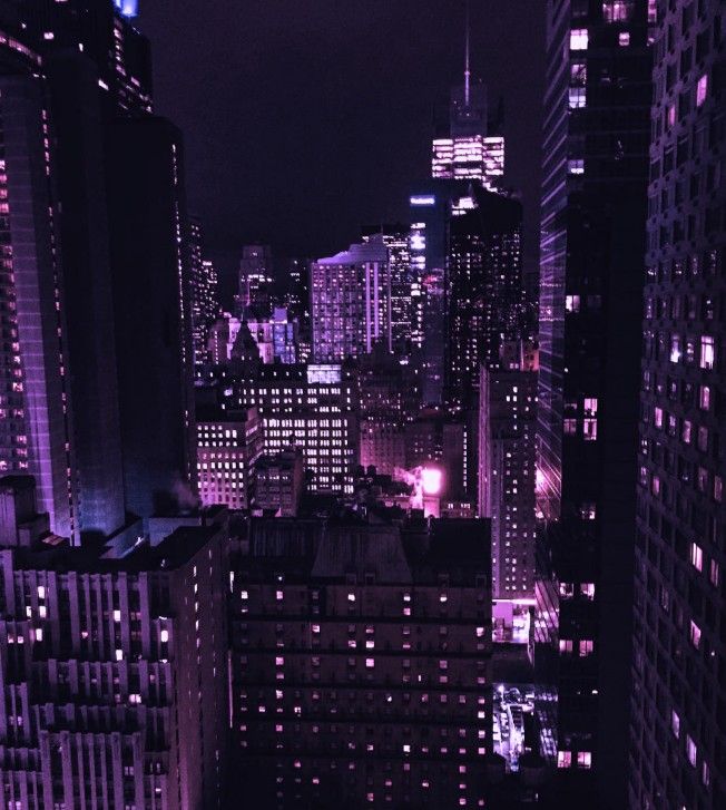 the city skyline is lit up at night with purple lights and skyscrapers in the background