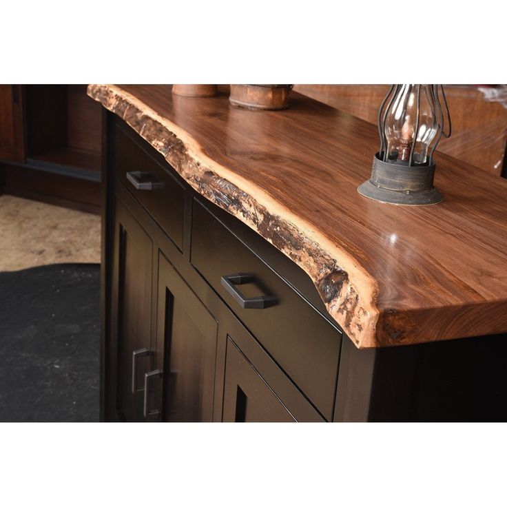 a wooden counter top sitting on top of a black cabinet next to a light bulb