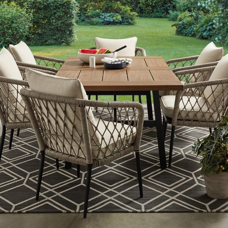 an outdoor dining table and chairs set up on a patio with grass in the background