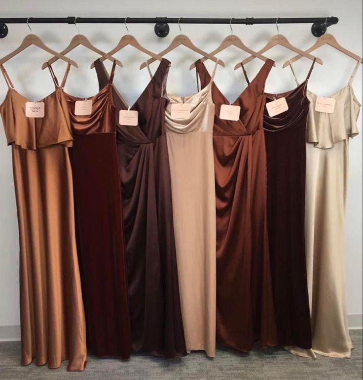 six dresses hanging on a rack in front of a wall