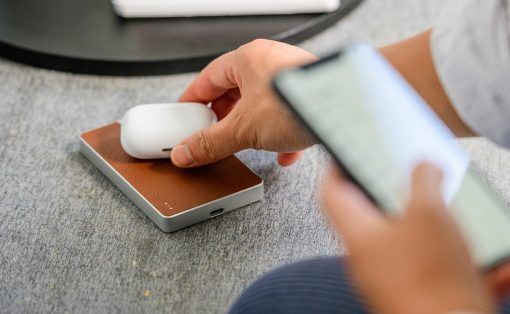 a person using a cell phone while sitting at a desk with a mouse and keyboard