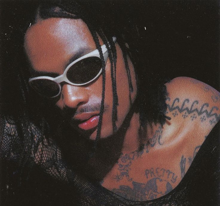 a man with sunglasses and tattoos on his arm posing for a photo in the dark