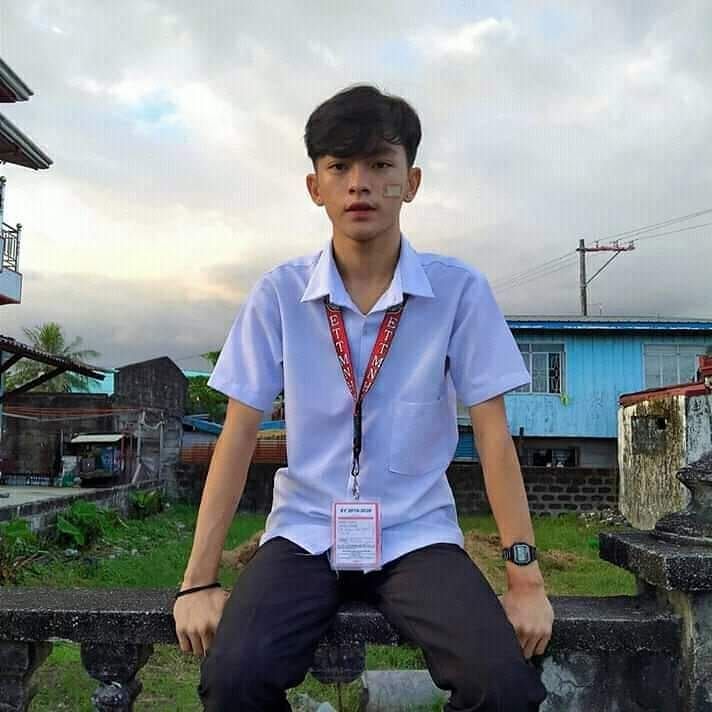 a young man sitting on top of a cement bench