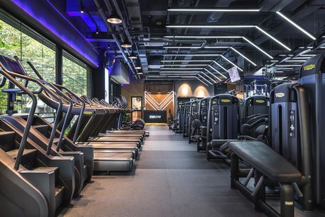 there are many treadmills lined up in this gym area with blue lighting on the ceiling