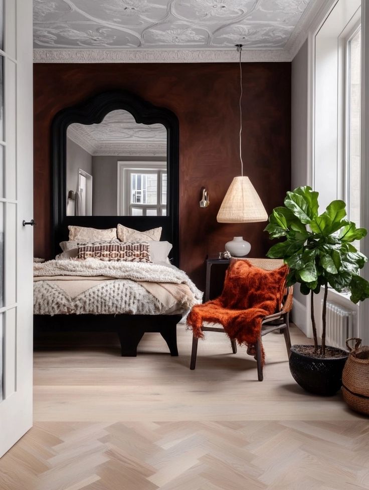 a bedroom with a bed, chair and mirror in it's corner next to a potted plant