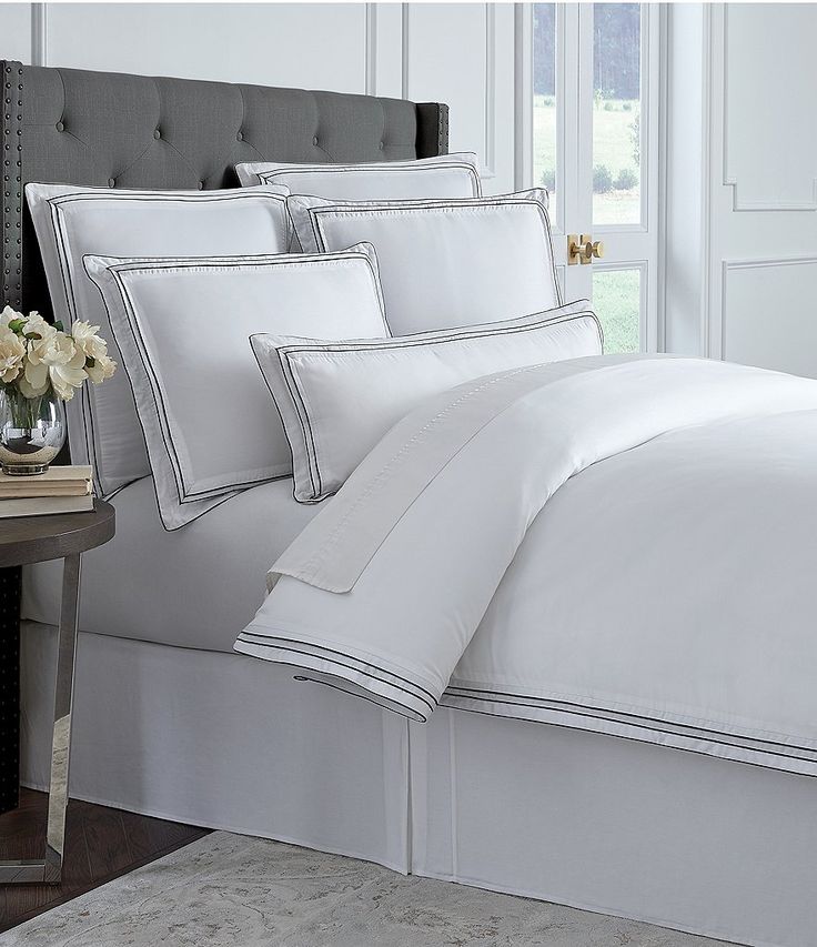 a bed with white sheets and pillows on top of it next to a night stand