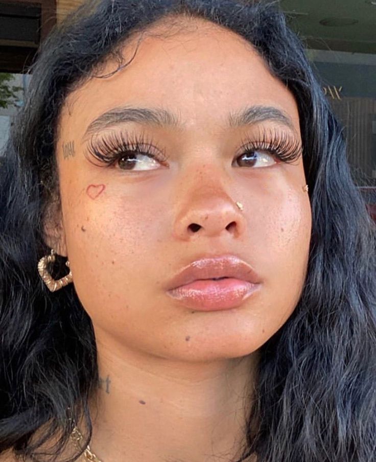 a close up of a person with long hair and piercings on her face,