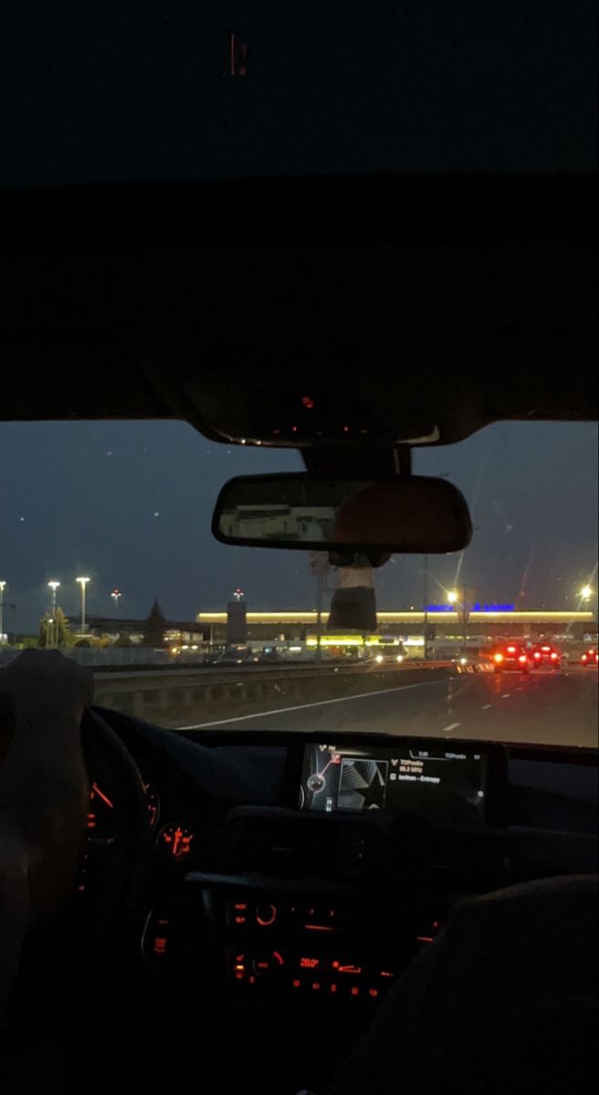 view from the inside of a car driving down an airport runway at night with lights on