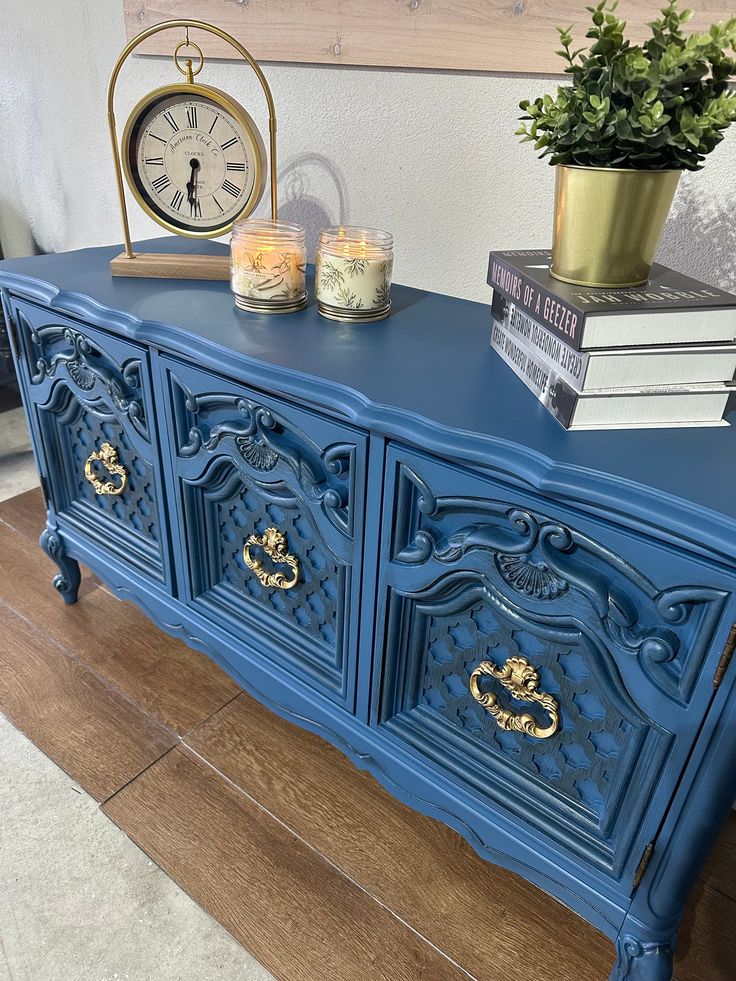 a blue sideboard with gold handles and drawers