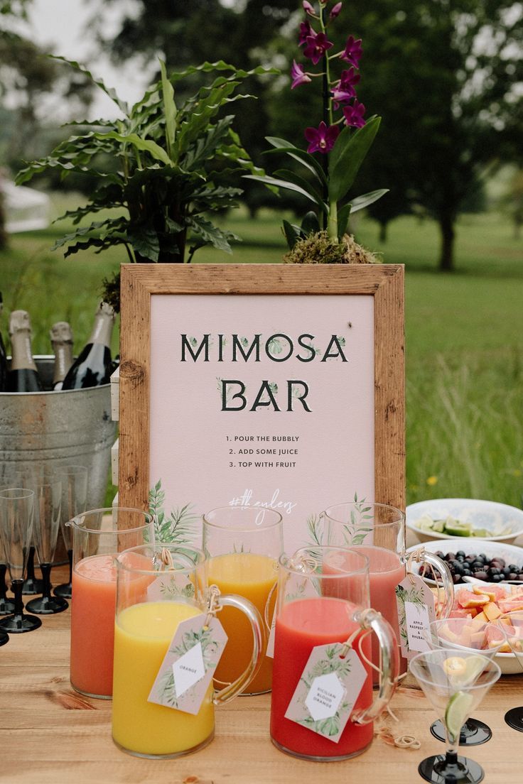 a sign that says mimosa bar next to some glasses with juice in them